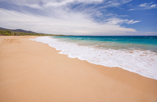 Sunny beach in Hawaii with golden sand, clear water under a bright sky
