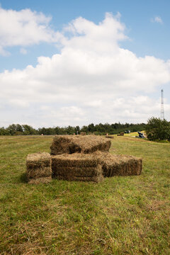 Hay bales stacked in green field with blue sky