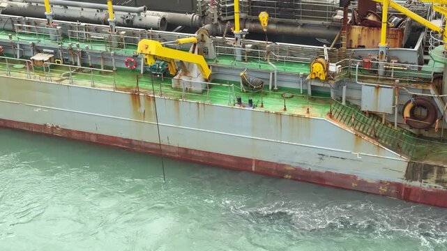 Commercial dredging ship carrying out coastal reclamation and seabed excavation operations in harbor waters.