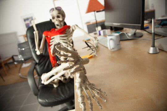Skeleton waiting at office desk reaching toward camera