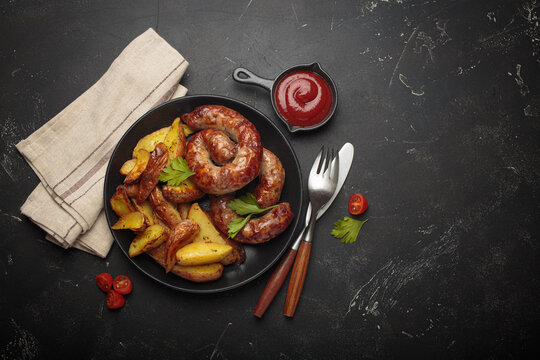 Fried coiled meat sausages roasted potatoes ketchup grilled bbq black plate barbecue copy space