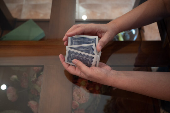 Close up of teenage hands shuffling a deck of playing cards on a glass table before a card game at home