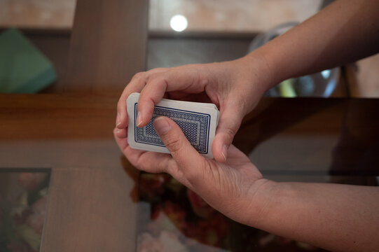 Close-up of a woman shuffling a deck of playing cards during a traditional card game at home