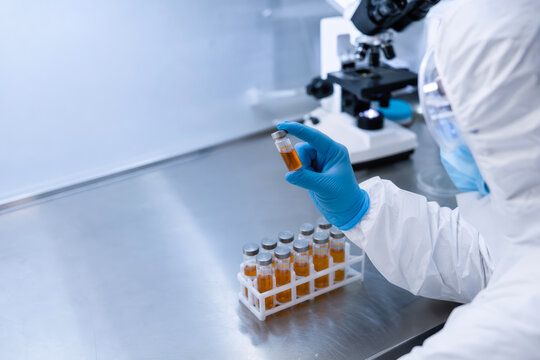 Marburg virus sample in sealed vial held by gloved researcher in hazmat suit on stainless lab bench with microscope and vial rack biosafety viral isolation genetic surveillance epidemiology