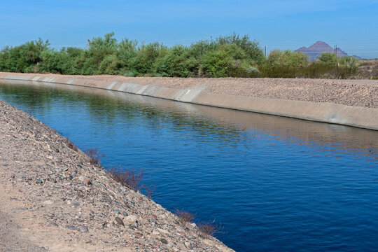 Concrete-lined irrigation canal carrying water through a desert landscape, illustrating water distribution, agricultural irrigation, infrastructure, and regional water management