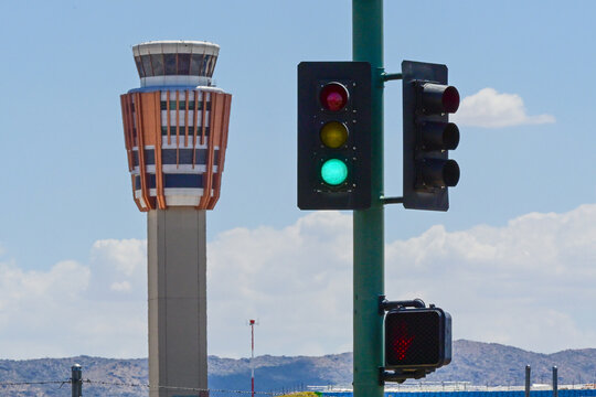 Green traffic signal with an airport air traffic control tower in the background, illustrating urban transportation, aviation infrastructure, and traffic management