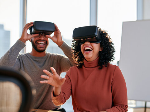Excited diverse colleagues laughing while experiencing virtual reality in a modern office
