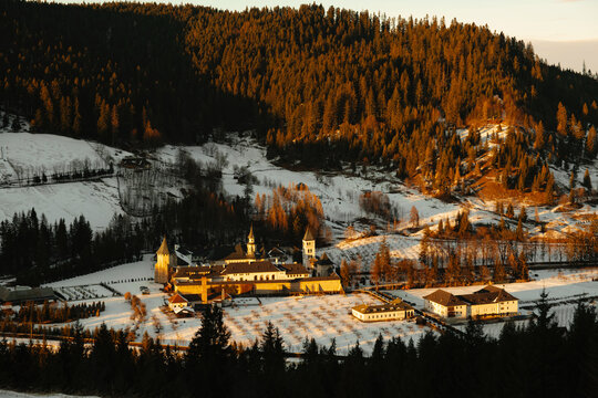 aerial view of a serene and peaceful monastery nestled in a snow-covered evergreen forest during wintera.