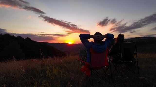 Man and woman looking at the sunset over the distant mountains.