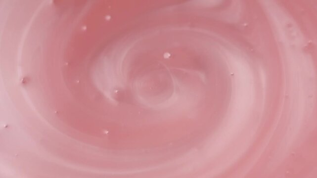 Liquid pink washing gel swirl texture soap, shampoo. Pearlescent surface of liquid pink fluid, background, shampoo texture, body care cosmetic, soap backdrop with bubbles top view from above, rotating