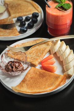A plate of crepes filled with chocolate spread and topped with banana slices and mint