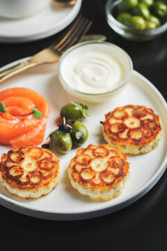 Savory Syrniki with Smoked Salmon, Olives and Sour Cream on White Plate