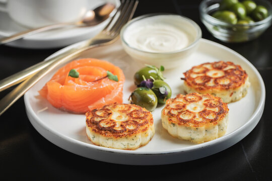 Savory Syrniki with Smoked Salmon, Olives and Sour Cream on White Plate