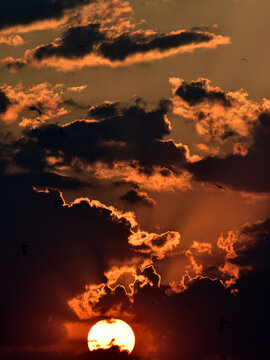 Dramatic view of the setting sun between the clouds. Vertical photo.