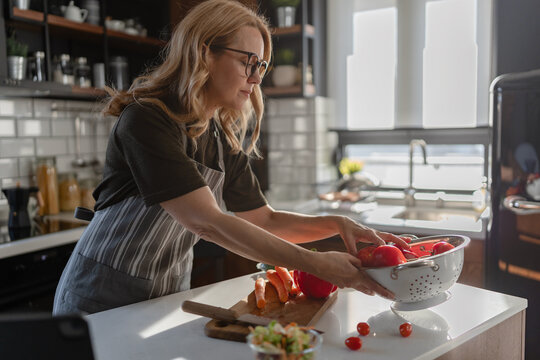 Woman preparing fresh ingredients for a homemade family meal in a contemporary kitchen. Everyday domestic life, cooking from scratch and healthy family nutrition