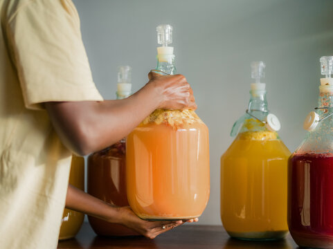 Woman is putting fermentation bottle on wooden counter 