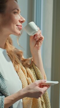 Calm Caucasian middle-aged woman drinking coffee inspired looking at window enjoying peaceful morning pause break at home relaxing smiling adult female drink tea aroma espresso beverage contemplating