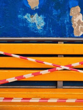 Caution tape on a wooden bench near a blue wall