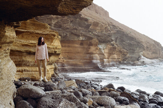 Woman exploring a rocky volcanic coastline in Tenerife, Canary Islands