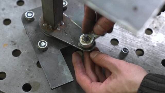 A worker tightens nuts and bolts into a transmission mechanism on bearings