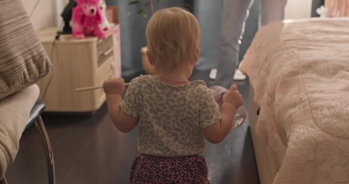 Toddler walking independently across a room toward mom. Early childhood milestone captured in a home environment