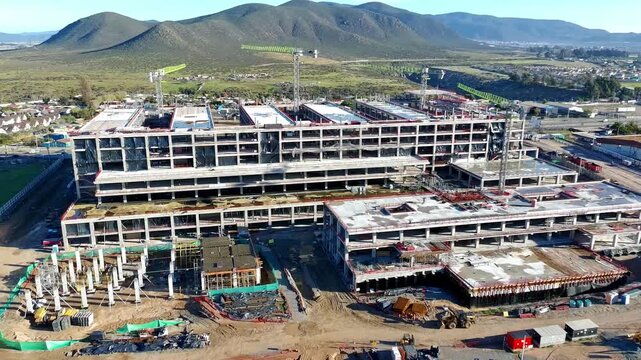 Close aerial view of hospital roof structure under construction with cranes Keywords extra: roof structure, exposed concrete, cranes, close aerial, top down