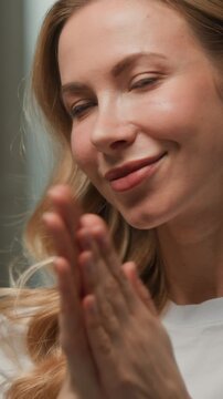 Close up portrait happy smiling Caucasian adult woman applying cream for facial massage in bathroom headshot cheerful joyful female massaging face and neck skincare procedure with natural cosmetics