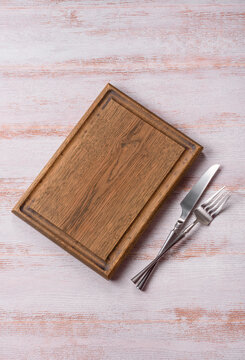 A square wooden cutting board for home food preparation. A wooden cutting board