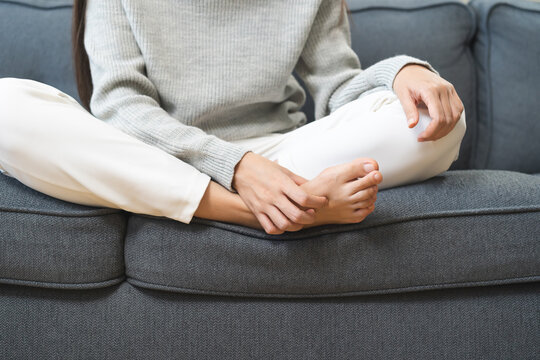 Foot pain, ache asian young woman hand scratch feet, itch foot, problem itchy skin on carpet at home, dermatitis from fungus, fungal bacterial infection, allergic reaction, eczema. Foot care concept.