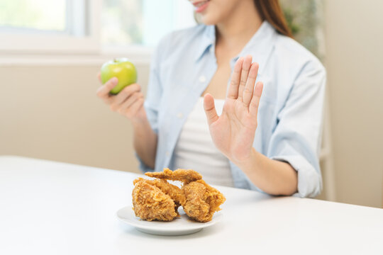 Diet, Dieting asian young woman hand push out, reject fried chicken on plate, deny to eat fast, junk food choose green apple or fruit, girl eat low fat for good healthy, getting weight loss people.