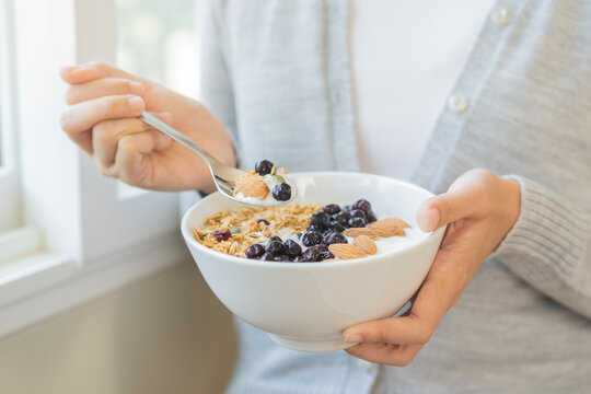 Healthy lifestyle, wellness food asian young woman hand use spoon eat tasty fresh organic yogurt, dairy product in bowl breakfast meal at home. Snack tasty on diet nutrition delicious natural yoghurt