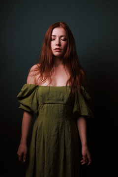 Red Haired Woman in Olive Green Dress With Closed Eyes Evoking Calmness Introspection and Quiet Serenity