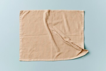 Fototapeta premium Plain beige cotton kitchen towel with soft folds on a light blue background for fabric mockup and textile design templates