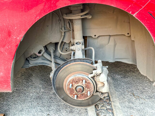 A close-up view of a car's front suspension and brake disc with the wheel removed during maintenance © Agustin