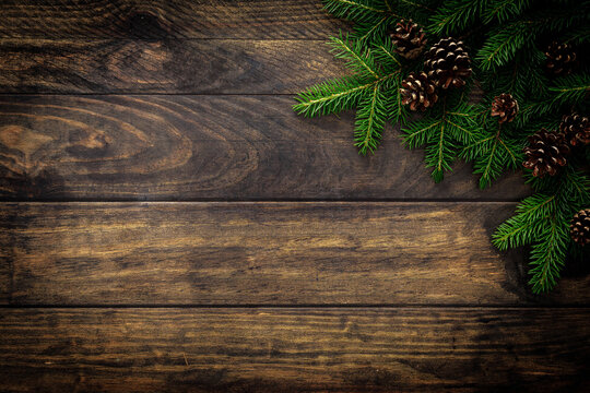 Christmas background with fir branches and pine cones on rustic wooden boards, christmas decoration