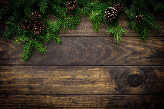 Christmas background with fir branches and pine cones on rustic wooden boards, christmas decoration