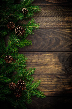 Christmas background with fir branches and pine cones on rustic wooden boards, christmas decoration
