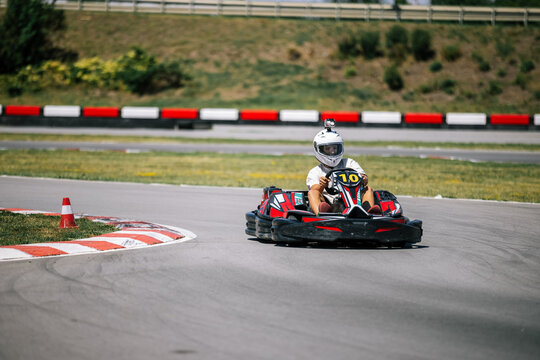 Teenage boy driving a go-kart and taking a sharp turn on an outdoor track