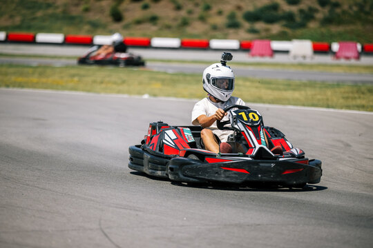 Teenage boy navigating a sharp turn in a go-kart race outdoors