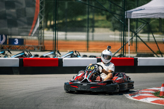 Close action view of a teenager driving a go-kart on a track curve