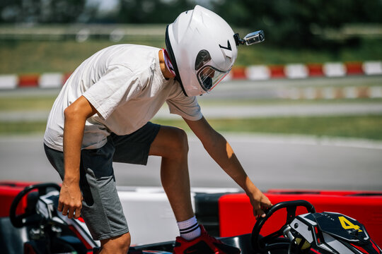 Young driver getting into a go-kart wearing a helmet with a camera
