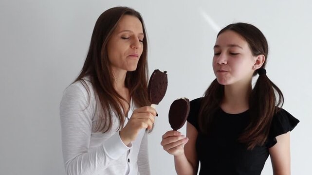 m&atilde;e e filha saboreando picol&eacute; delicioso de chocolate 
