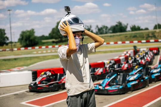 Teenage boy finishing a go-kart race and pulling off his helmet