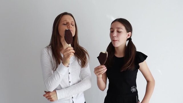 m&atilde;e e filha saboreando picol&eacute; delicioso de chocolate 
