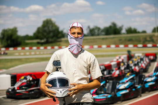 Teenager wearing a headscarf and holding a racing helmet while looking at the camera
