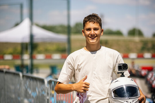 Teenage boy smiling and giving a thumbs up while holding a go-kart helmet