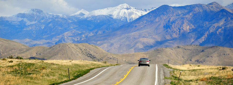 Car Driving on Highway or Roady Towards Snow Topped Mountains in Wilderness