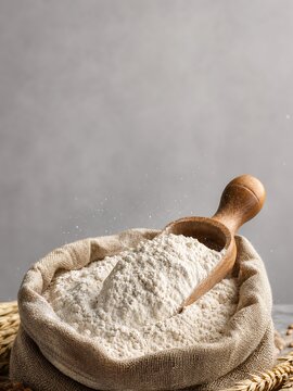 Organic whole wheat flour in burlap sack with wooden scoop depicting authentic artisan bakery and home baking process