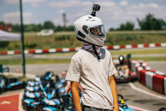Teenage boy wearing a racing helmet while standing at an outdoor go-kart track