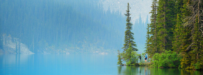 Obraz premium Hikers or Tourists on Point of Land Out in Wilderness Lake High in the Mountaiins